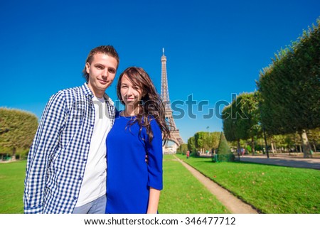 Young happy couple on the Champ de Mars in Paris background the Eiffel Tower 