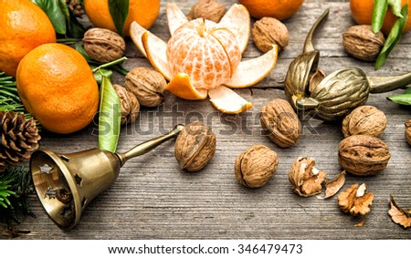 Tangerine fruits, walnuts and christmas tree branches on wooden background. Vintage style toned picture