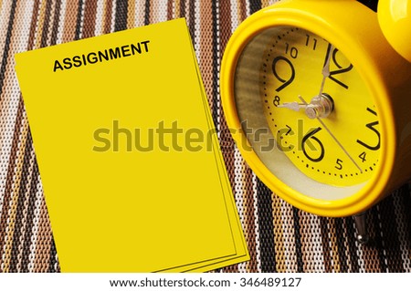 Yellow assignment notes beside close up retro alarm clock on color mat shows 8 oclock