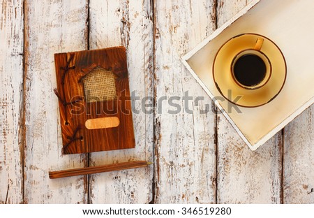 top view image of cup of coffee on wooden white tray and notebook, over wooden table
