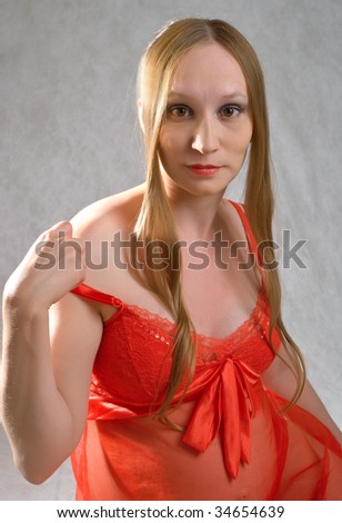 Portrait of young pregnant women in red on grey background