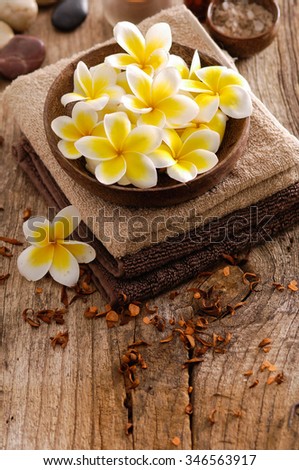 frangipani in bowl and dry flower petals ,towel ,oil on old wood

