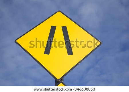 Road Narrowing Sign against Blue Sky Background