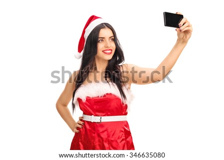 Young woman in Santa outfit taking a selfie with her cell phone isolated on white background