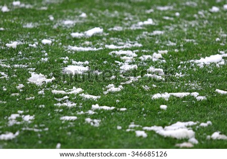 Green grass on a football soccer field covered with a snow