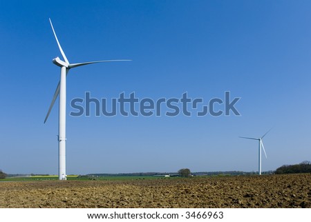 Two wind turbines in country. Empty space in upper right corner on blue sky background.