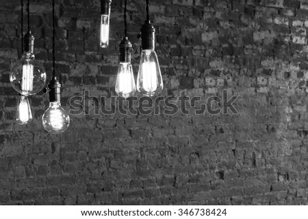 Decorative antique edison style light bulbs against brick wall background Royalty-Free Stock Photo #346738424