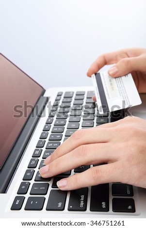 Vertical picture of Human next to laptop with credit card on white background