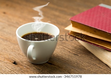 Education concept. Hot coffee with old book on grunge wood table.