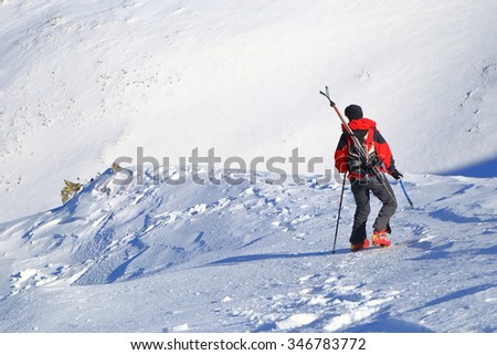 Mountaineer woman carries skis on the backpack while descending ice covered slope
