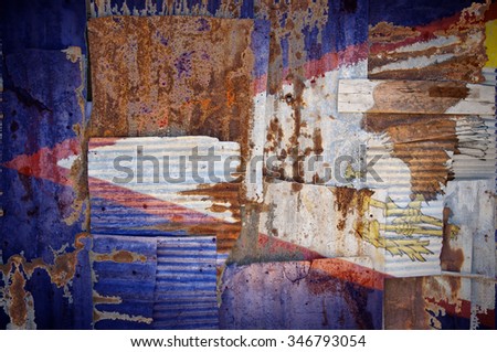 An abstract background image of the flag of American Samoa painted on to rusty corrugated iron sheets overlapping to form a wall or fence.