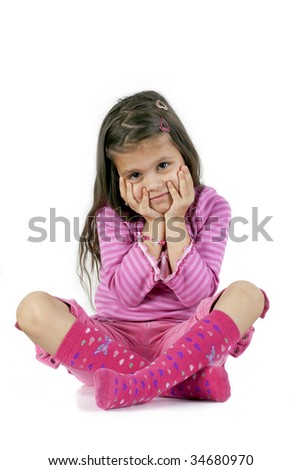 young girl sits with her legs crossed and hands on Face.