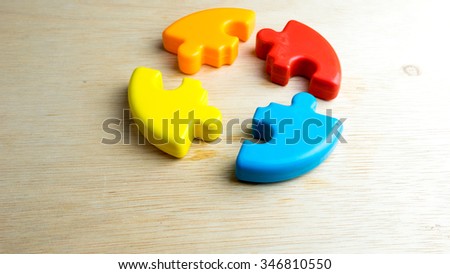 Cute and multicolor plastic pie chart or puzzle on wooden surface. Concept of process solution and teamwork collaboration. Slightly de-focused and close-up shot. Copy space.