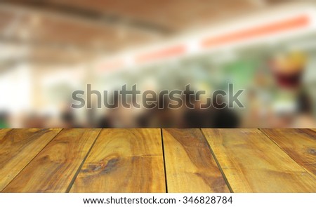 Wooden table and  blurred image people in food center with light bokeh