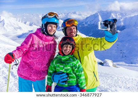 Skiing, winter fun - happy family taking picture at the ski slope