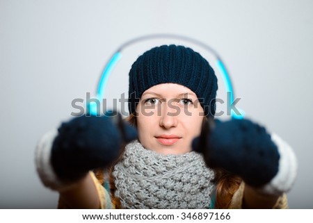 beautiful girl gives listen to headphones, lifestyle winter clothes studio photo isolated on a gray background