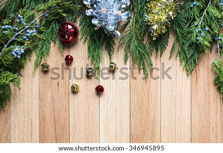 christmas jingle bells on hard wood floor background with green leaves top frame 