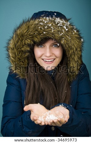 Woman wearing fur-lined parka and holding snow