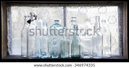 Stock photo of empty antique glass bottles on old narrow window against daylight. 
