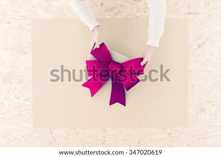 Female hands holding big bow on table