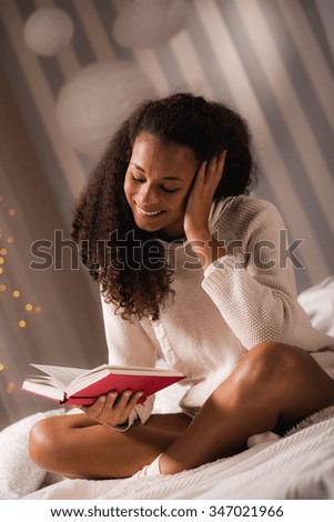 Picture of girl reading funny book at cold winter evening