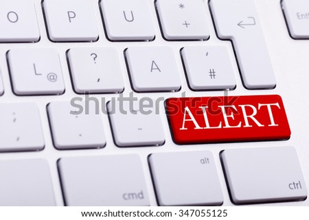 Alluminium keyboard with alert word written on red button close up photo