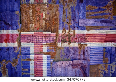 An abstract background image of the flag of Iceland painted on to rusty corrugated iron sheets overlapping to form a wall or fence.