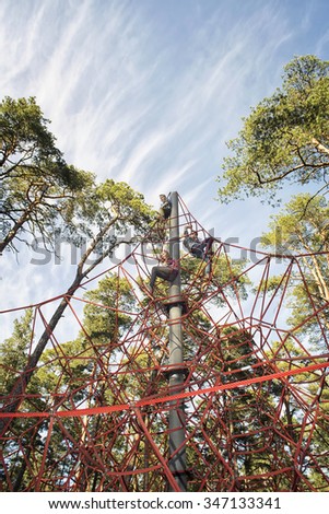 Red jungle gym ropes against blue cloudy sky in a park. Network game for children to climb.