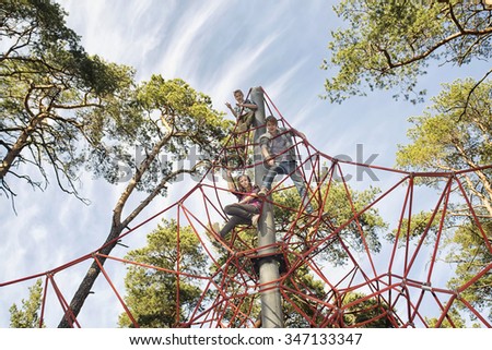 Red jungle gym ropes against blue cloudy sky in a park. Network game for children to climb.