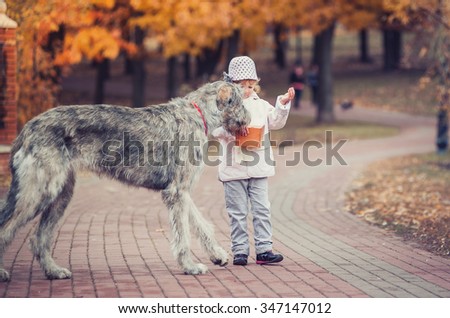 Girl with a lollipop and a big dog walk in the park Royalty-Free Stock Photo #347147012