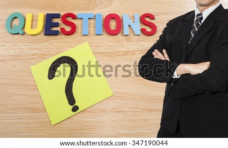 One business man wear black suit stand on Questions background (Business Concept)