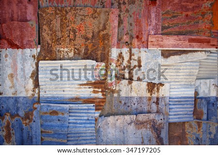 An abstract background image of the flag of Paraguay painted on to rusty corrugated iron sheets overlapping to form a wall or fence.
