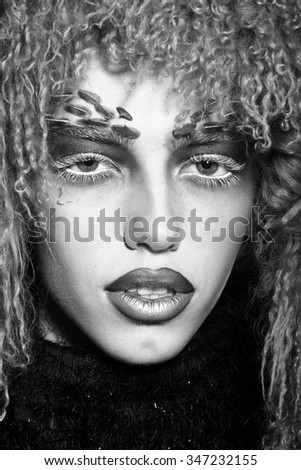 Closeup portrait of one beautiful wild young woman with bright animal monkey makeup with thorns on face in fur wig in studio, vertical picture