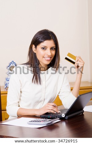 beautiful young woman holding a bank credit card and doing online shopping
