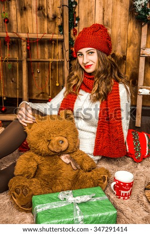 beautiful girl sits with gifts in a room with wooden walls. Christmas and New Year concept