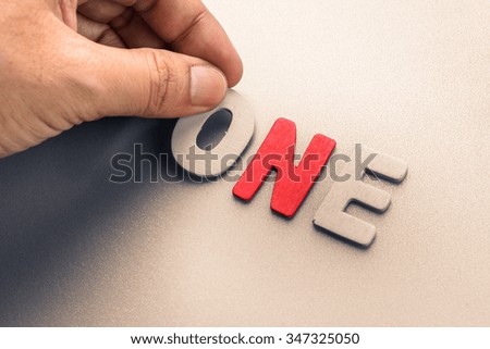 Hand arrange wood letters as One word