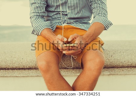 young hipster guy holding a smartphone responds to mail texting and send pictures while sitting on the pier,Young man wearing blank t-shirt and blue jeans, standing on the street,periscope,instagram