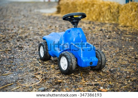 Children blue toy tractor outside in rain