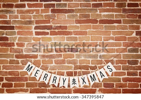 Black and white MERRY XMAS and twig tree card homemade flag garland decoration on rustic red yellow brown brick wall background. Horizontal postcard with space for text, copy or lettering.
