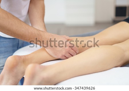Close up Male Physical Therapist Massaging the Leg of a Patient Who is Lying on Therapy Bed.