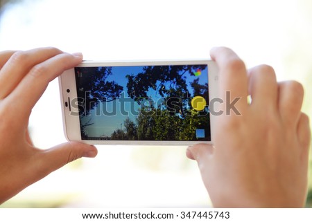 Human hands taking photo with mobile phone, outdoors