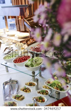 Assorted fresh salads displayed on a buffet, individual containers at catered event or celebration, receding perspective