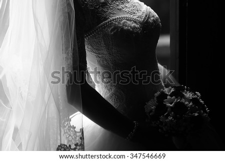 Photo closeup of beautiful young bride in ornamental wedding lace dress long veil holding elegant bouquet of fresh flowers for bridal ceremony black and white on grey background, horizontal picture
