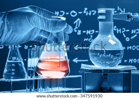 Flask in scientist hand with boiling liquid in round bottom flask