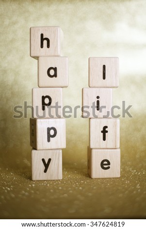happy and life text on wooden block on golden background