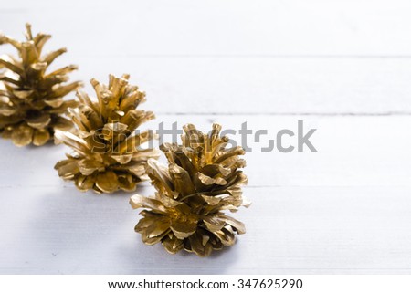 golden pine cones Christmas decoration on white wood table background