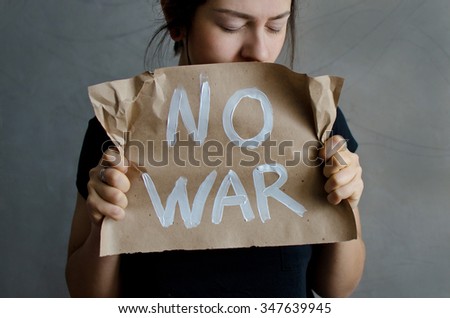 woman holding a sheet of craft paper with white color inscription no war