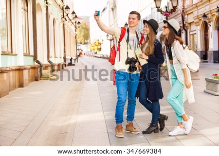 Guy and two girls taking selfies with mobile phone