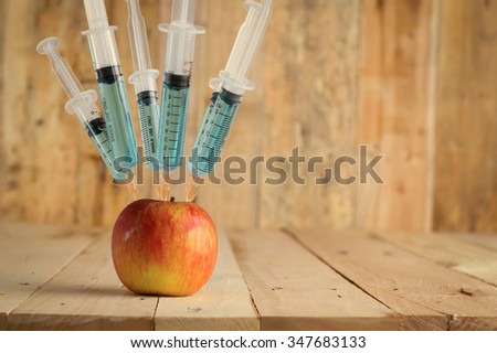 Injection into red apple -  Concept for Genetically modified fruit and syringe with colorful chemical GMO food Royalty-Free Stock Photo #347683133