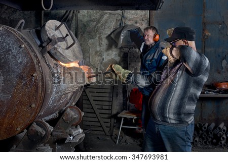 Young worker prepares a special form of land for the casting of molten aluminum